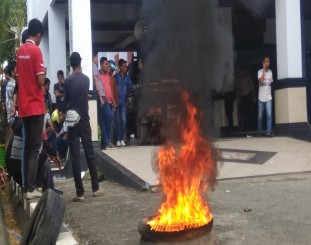 Massa aksi saat membakar ban bekas di kantor Walikota kendari